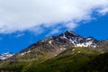 Muntain in early summer covered by forest and little snow on the top