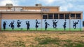 Mural on an outside school wall with graduates in Cap and Gown jumping for joy in Dallas, Texas.