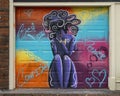 Mural painted on a pull down garage door featuring themes of confidence, power and self-love for women in Deep Ellum in Dallas.