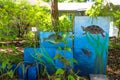 A mural of turtles, fish and frogs painted on blue cinder blocks surrounded by lush green plants at Newman Wetlands Center