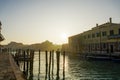 Murano, Italy day golden hour on canal with low-rise colorful buildings and moored boats on wooden wharf pilings Royalty Free Stock Photo