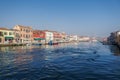 Murano, Italy day view of main canal with low-rise colorful buildings and moored boats on wooden wharf pilings Royalty Free Stock Photo