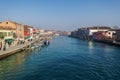 Murano, Italy day view of the main canal with low-rise colorful buildings and moored boats on wooden wharf pilings Royalty Free Stock Photo