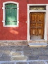 Murano, Italy - February 2019: Beautiful details of a faÃÂ§ade in Italy, red house with green window and wooden door