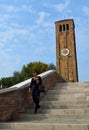 Female Tourist on Bridge on the Island of Murano Venice, bell tower in background.