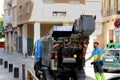 Murcia, Spain - August 4 2018: Waste management operative emptying a domestic rubbish or garbage bin into a small refuse truck be