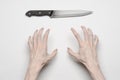 Murder and Halloween theme: A man's hand reaching for a knife, a human hand holding a knife isolated on a gray background in Royalty Free Stock Photo