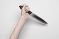 Murder and Halloween theme: A man's hand reaching for a knife, a human hand holding a knife isolated on a gray background in Royalty Free Stock Photo