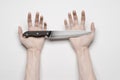 Murder and Halloween theme: A man's hand reaching for a knife, a human hand holding a knife isolated on a gray background in Royalty Free Stock Photo