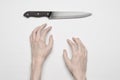 Murder and Halloween theme: A man's hand reaching for a knife, a human hand holding a knife isolated on a gray background in Royalty Free Stock Photo