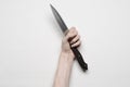 Murder and Halloween theme: A man's hand reaching for a knife, a human hand holding a knife isolated on a gray background in Royalty Free Stock Photo