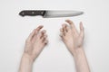 Murder and Halloween theme: A man's hand reaching for a knife, a human hand holding a knife isolated on a gray background in Royalty Free Stock Photo