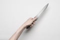 Murder and Halloween theme: A man's hand reaching for a knife, a human hand holding a knife isolated on a gray background in Royalty Free Stock Photo