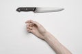 Murder and Halloween theme: A man's hand reaching for a knife, a human hand holding a knife isolated on a gray background in Royalty Free Stock Photo