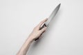 Murder and Halloween theme: A man's hand reaching for a knife, a human hand holding a knife isolated on a gray background in Royalty Free Stock Photo