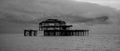 Murmuration of starlings over the remains of West Pier, Brighton UK. Photographed at dusk. Photographed in monochrome.