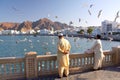 Locals feeding seagulls at Muttrah corniche with Sur Al Lewatia Mosque in the background