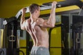 Muscle athlete man in gym making elevations. Bodybuilder training in gym