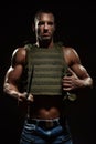 Military style muscle man in tactical vest posing with survival knife