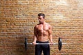 Muscle shaped body man with weights on brick wall