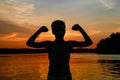 Muscle silhouette of boy at lake during sunset