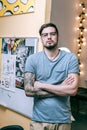 Muscled good-looking man crossing his hands covered in tattoos