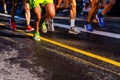 Muscled legs of a group of several runners training running on asphalt