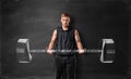 Muscled young man lifting hand drawn weight on the background of blackboard