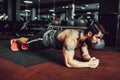 Muscled young man wearing sport wear and doing plank position while exercising on the floor in loft interior Royalty Free Stock Photo