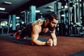 Muscled young man wearing sport wear and doing plank position while exercising on the floor in loft interior Royalty Free Stock Photo