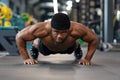 Muscular african american athlete training on floor at gym