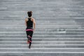 Muscular african american girl in sportswear runs up the stairs in city