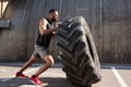 muscular african american sportsman exercising with tire on street