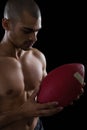 Muscular American football player looking at football in both his hands Royalty Free Stock Photo