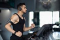 Muscular Arab Male Athlete Wearing Wireless Headphones Running On Treadmill At Gym Royalty Free Stock Photo