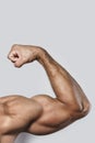 Muscular arm of young bodybuilder on gray background