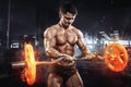 Muscular athlete bodybuilder with burning barbell concept in gym