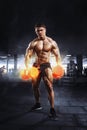 Muscular athlete bodybuilder lifting weight with flaming biceps