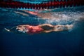 Muscular athlete. Competitive woman, professional female swimmer training in swimming pool indoor. Underwater view Royalty Free Stock Photo