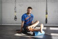 Muscular athlete exercising yoga asana in sunny sport club, brick wall. Fit shirtless male fitness model.