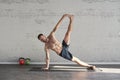 Muscular athlete exercising yoga trikon asana in sunny sport club, brick wall. Fit shirtless male fitness model. Royalty Free Stock Photo