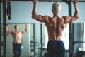 Muscular athlete man making Pull-up in gym. Bodybuilder training in fitness club showing his perfect back and shoulder Royalty Free Stock Photo