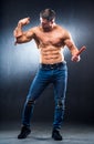 Muscular athlete with naked torso playing muscles with smoked sausage in one hand and sausages on a neck Royalty Free Stock Photo