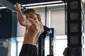 Muscular athlete pulling up on horizontal bar at gym