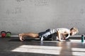 Muscular athlete tattooed body exercising plank workout in sunny sport club, brick wall. Fit shirtless male fitness model. Royalty Free Stock Photo