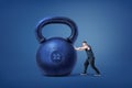 A muscular athlete ties to push and move from its place a huge iron kettlebell.