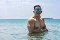 A muscular and athletic asian man wearing shades has a good time while taking a dip in the sea. Summertime body goals for the Royalty Free Stock Photo