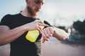 Muscular bearded athlete checking burned calories on electronic smart watch application after good workout outdoor