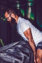 Muscular bearded fitness man flipping heavy tire at gym Royalty Free Stock Photo