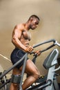 Muscular black male bodybuilder exercising on step machine in gym